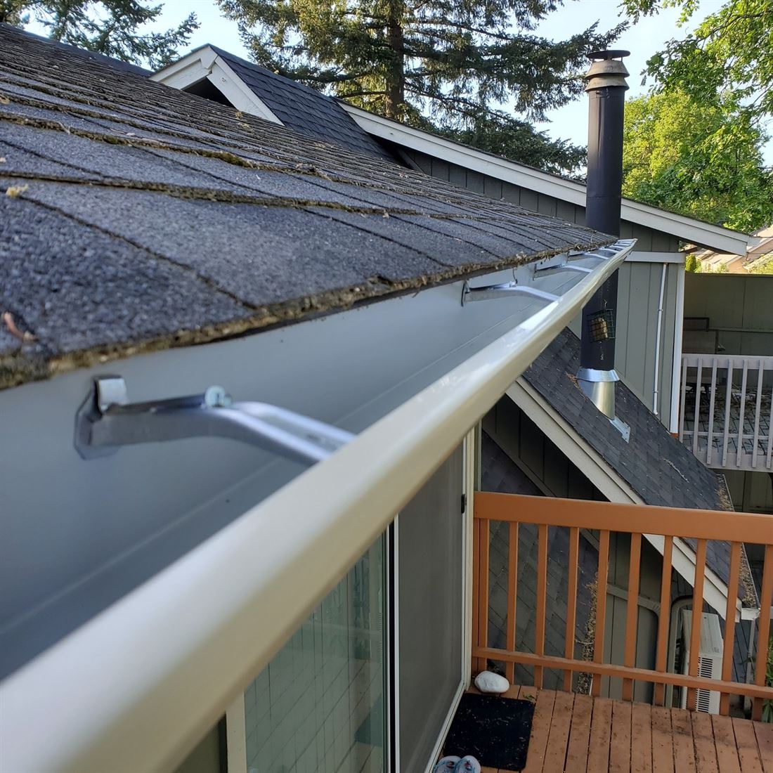A newly installed seamless aluminum gutter with hidden hangers along a shingle roof in Eugene, Oregon